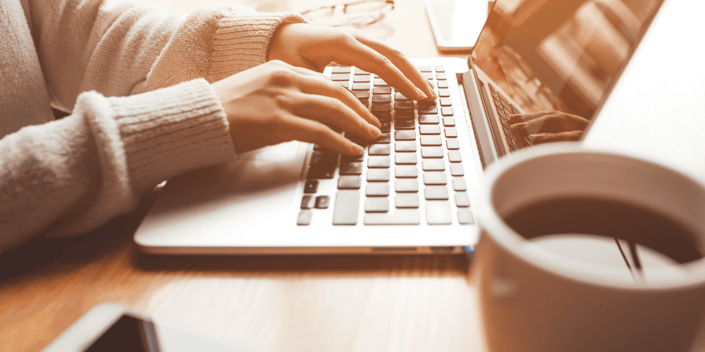 woman typing on laptop to demonstrate working on goals and building confidence
