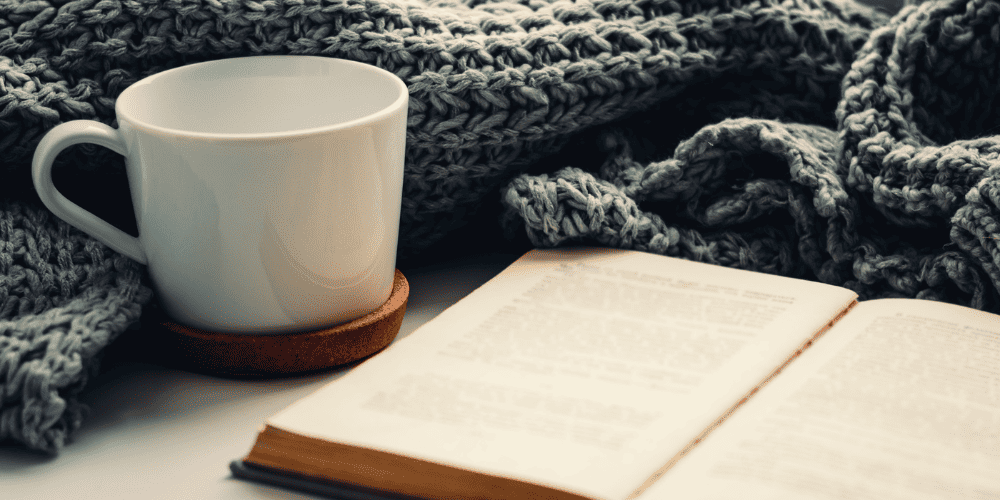 Cup of coffee and open journal under a blanket to demonstrate doing a daily gratitude exercise