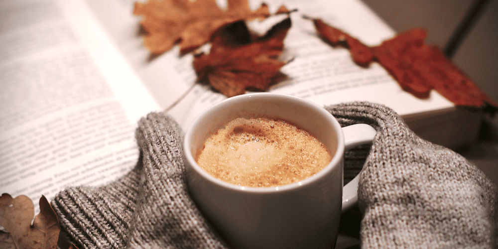 Hands holding a cup of coffee on a fall day