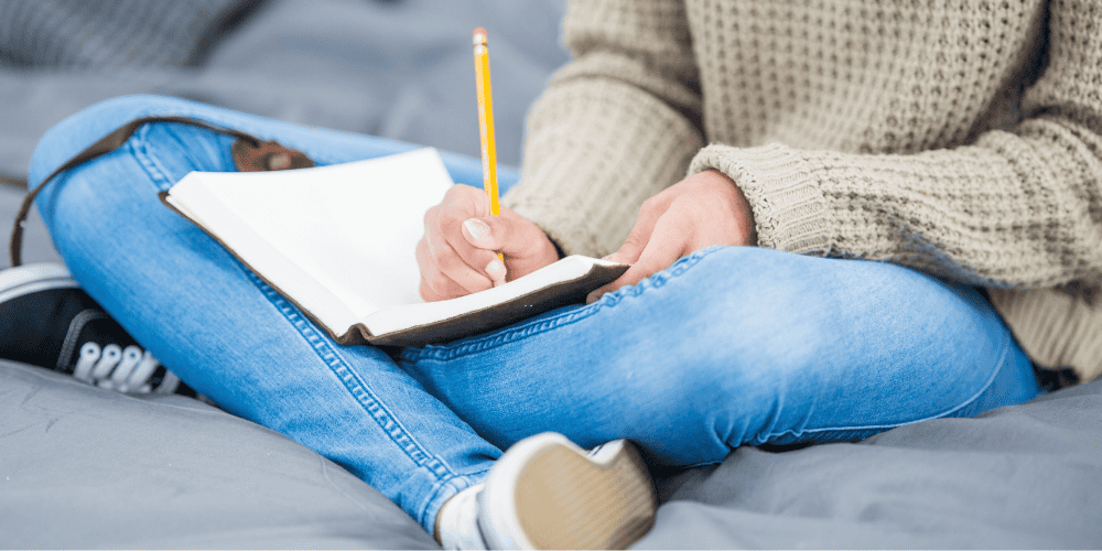 Woman writing in a journal to demonstrate using journal prompts to find direction when you feel lost in your career
