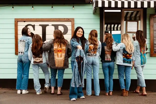 Kelly in front of her coffee stand business holding a jacket from her custom jacket business to motivate women to start their own business