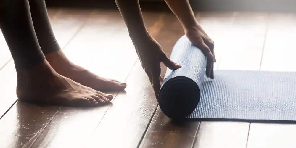 Woman rolling out yoga mat to demonstrate the importance of a good morning routine